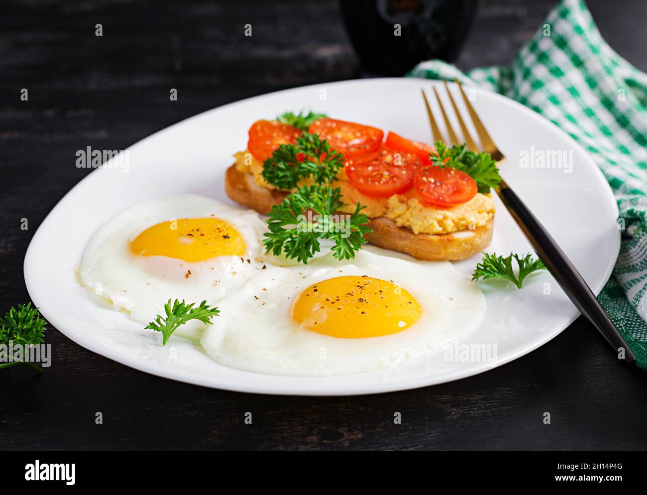Des œufs frits et un sandwich au pâté de poulet grillé sur fond sombre. Banque D'Images