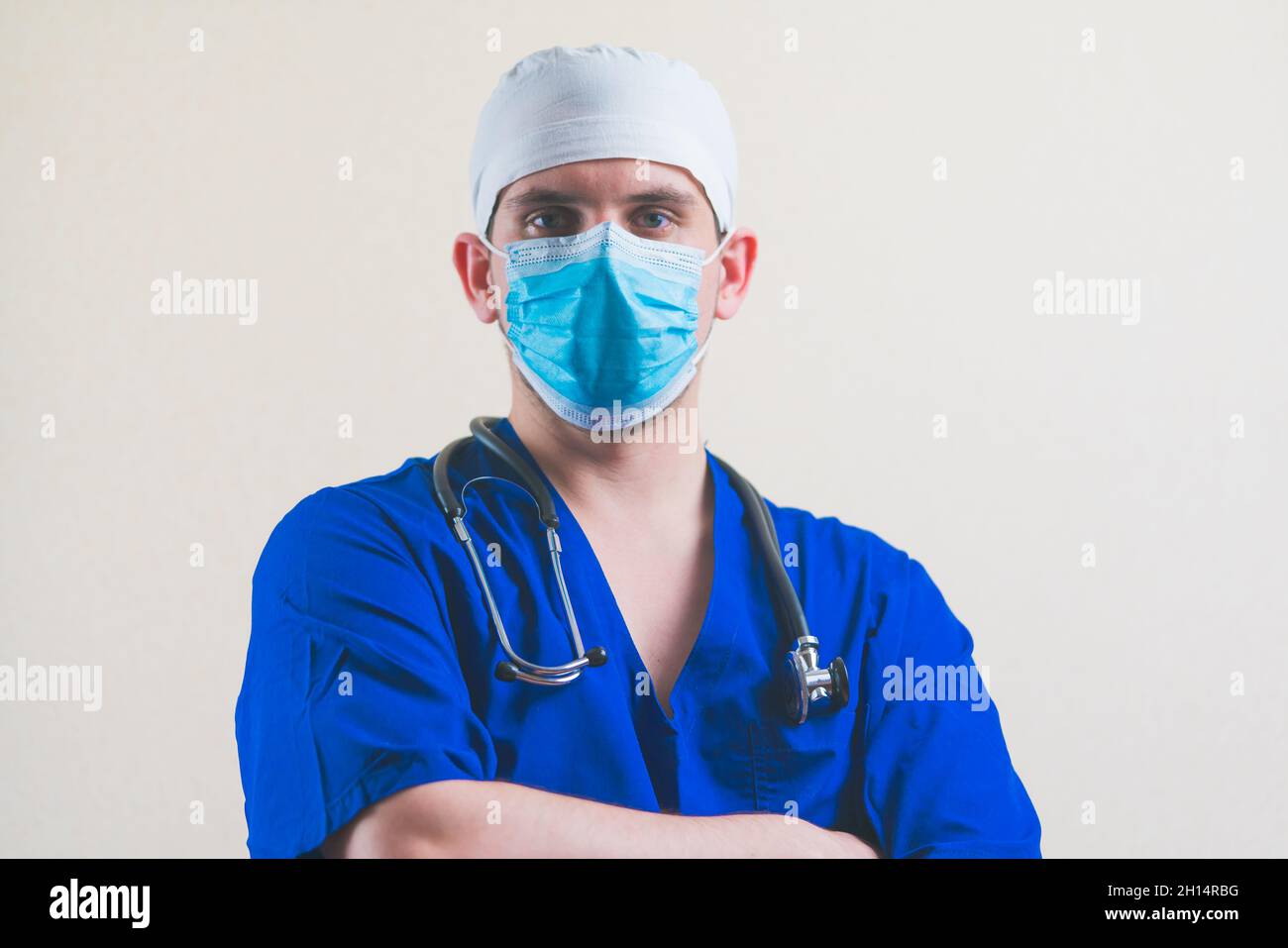Portrait de jeune médecin en costume bleu avec stéthoscope et avec ses mains sur sa poitrine isolée sur fond lisse Banque D'Images
