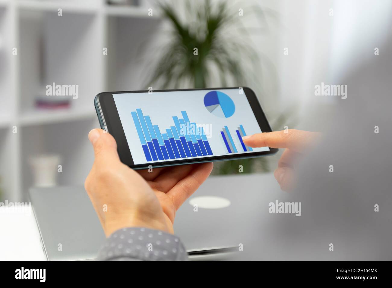 Business Woman analyse des statistiques, des graphiques et des graphiques de ventes sur un écran de téléphone mobile. Banque D'Images