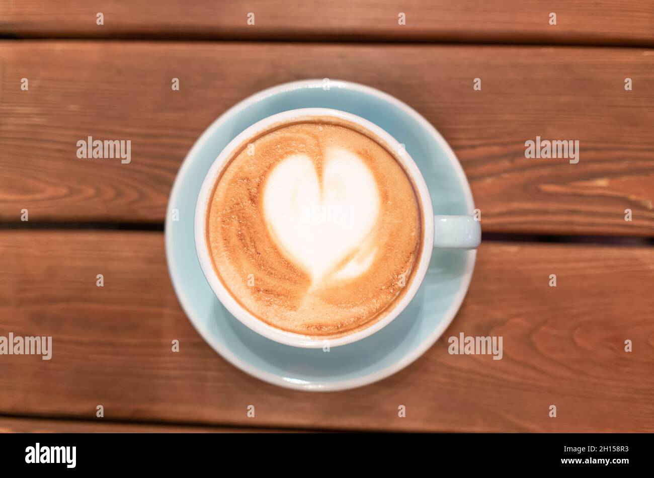 Coeur de mousse de café dans une tasse bleue sur une table en bois, vue de dessus.Cappuccino ou mocha le matin dans un café.Latte Art Banque D'Images