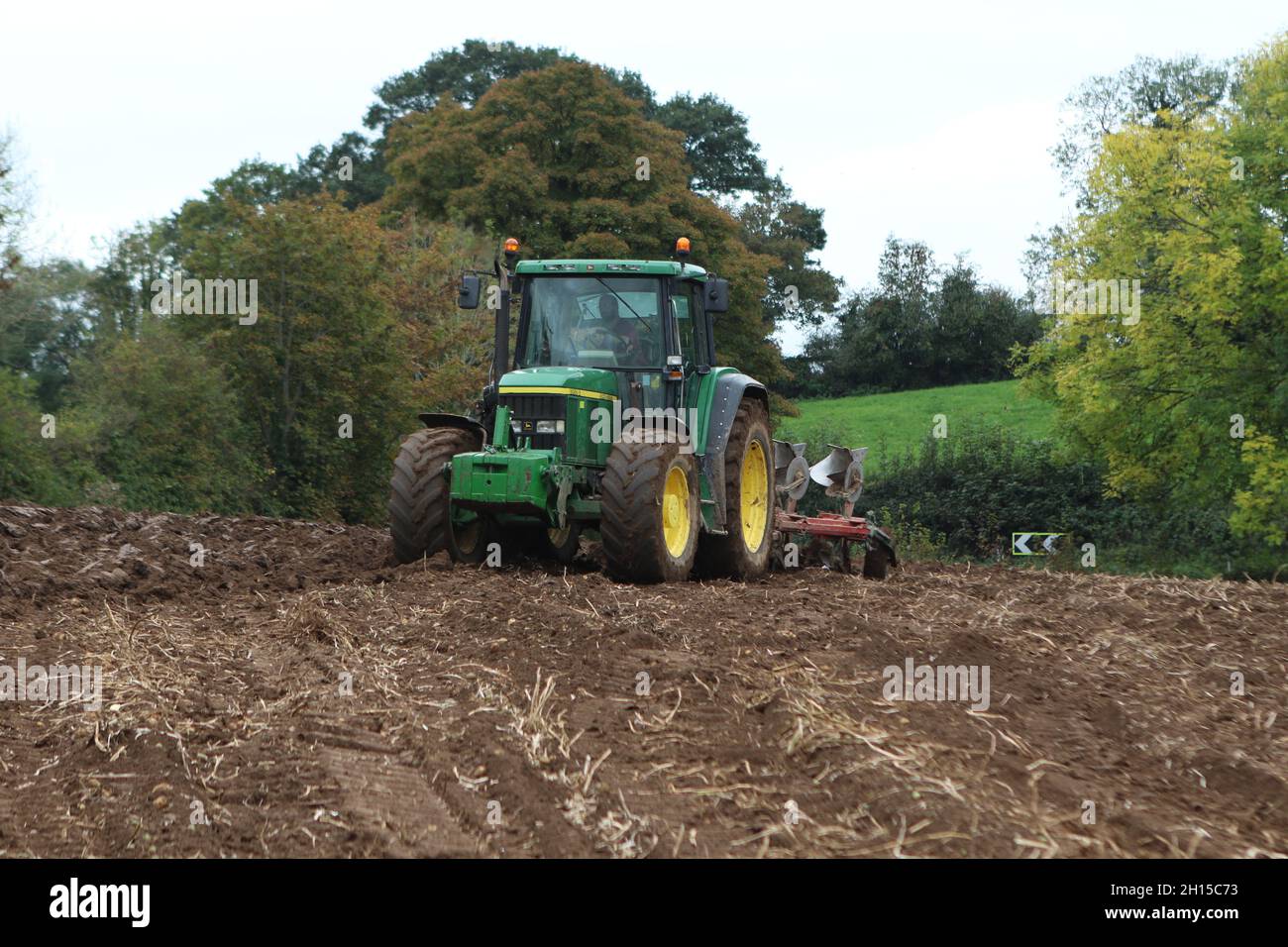 Tracteur John Deere 6910s vert avec charrue réversible à 4 sillons travaillant dans un champ Banque D'Images