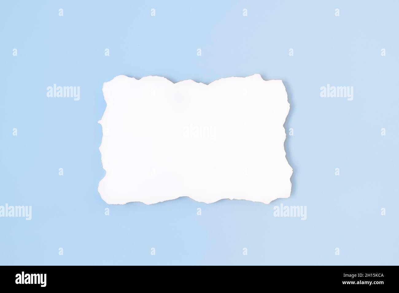 Papier blanc vierge vide avec bordure inégale sur fond bleu clair.Maquette de carte d'invitation sur une table bleu pâle.Flat lay, vue de dessus, espace de copie, maquette Banque D'Images
