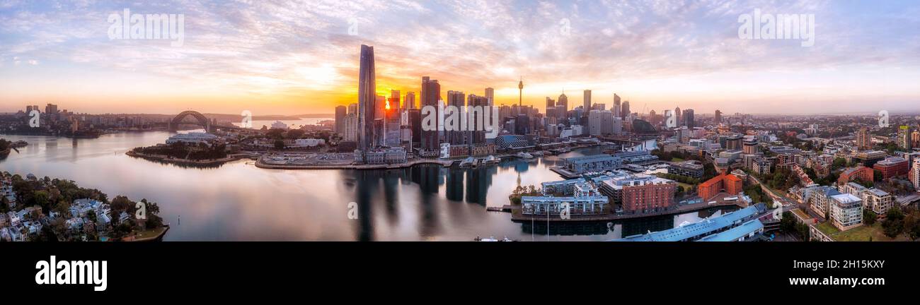 Large panorama aérien au lever du soleil au-dessus de la ville de Sydney, avec des tours du quartier des affaires qui cachent le soleil levant sur les rives du port de Sydney et les principaux monuments architecturaux. Banque D'Images