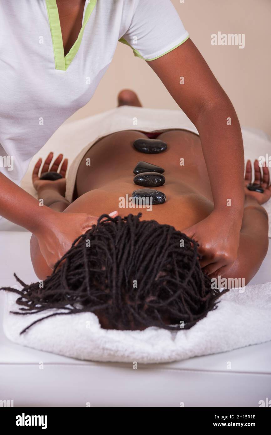 Massage thérapeutique, massage aux pierres chaudes, femme africaine sur le lit Banque D'Images