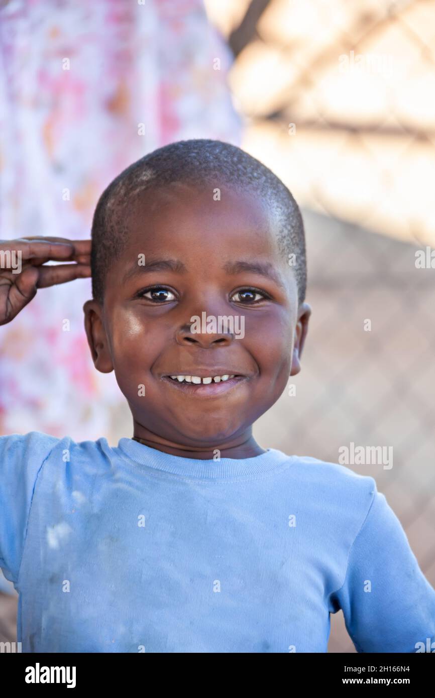 Portrait d'enfant africain dans un village dans la campagne Botswana saluant les étrangers de la route en face de la maison Banque D'Images