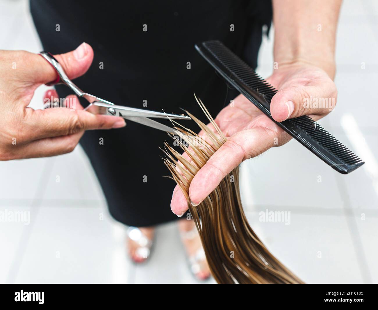 Rognez un coiffeur méconnaissable en utilisant des ciseaux pour couper les cheveux justes du client dans le salon de beauté Banque D'Images