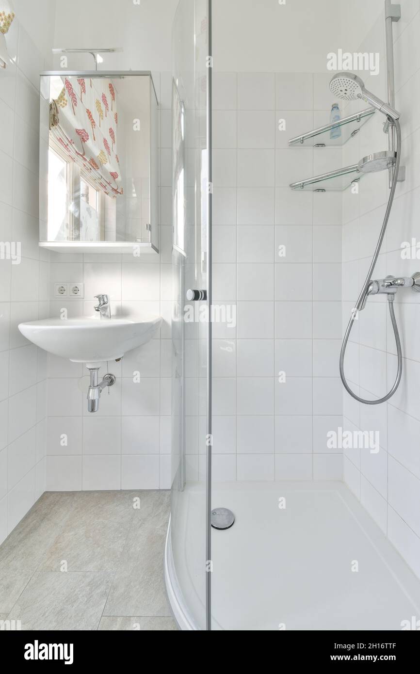 Cabine de douche et lavabo en céramique sous armoire à miroirs accrochée au  mur de carrelage blanc dans salle de bains minimaliste à la lumière du  soleil Photo Stock - Alamy