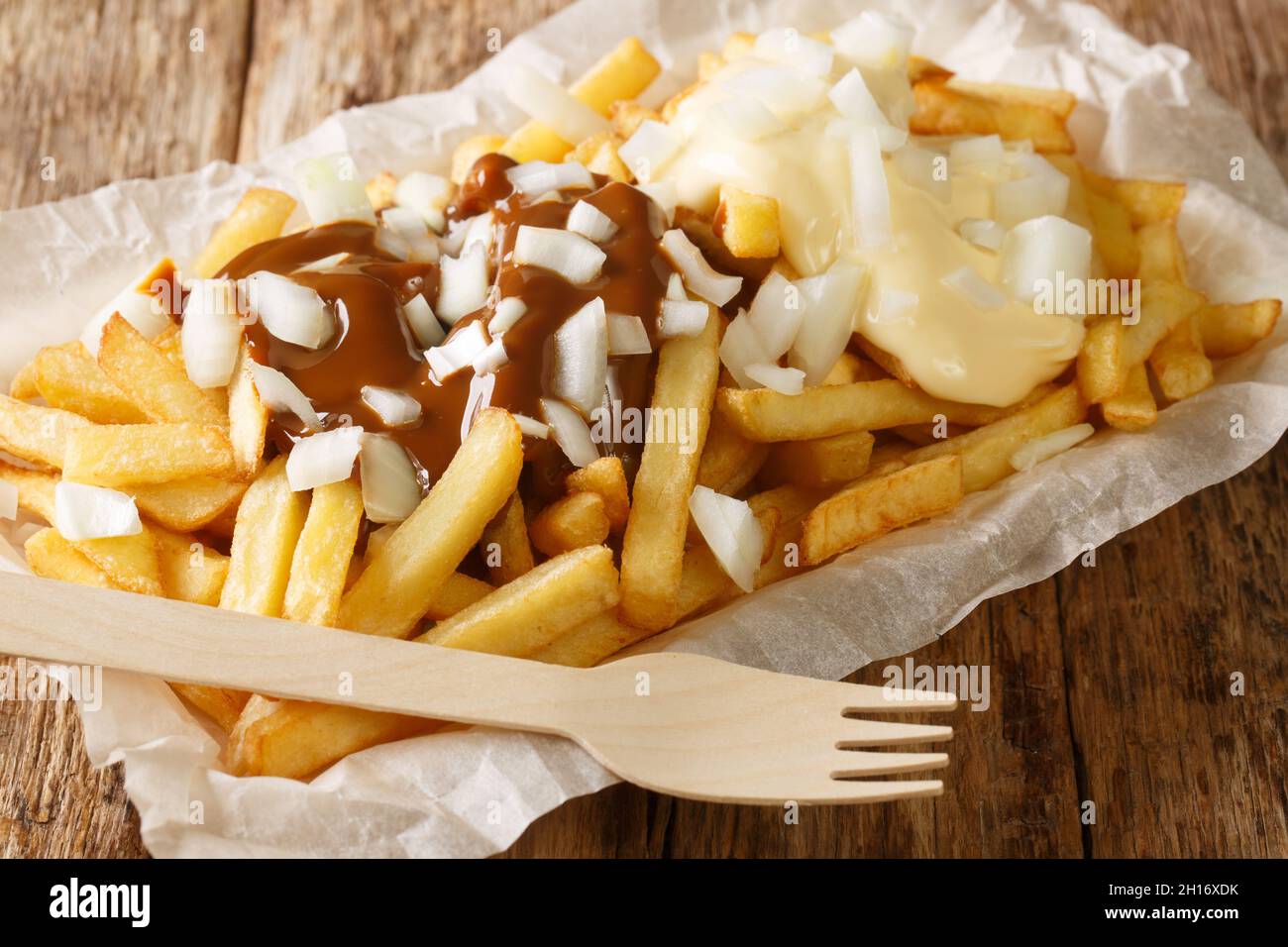 Plats à emporter néerlandais Patatje oorlog frites avec sauces et oignons frais gros plan dans une assiette sur la table. Horizontal Banque D'Images