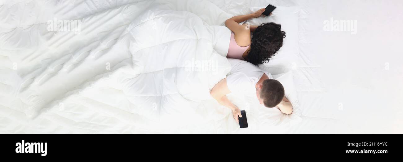 Homme et femme allongé dans la chambre à coucher sur le lit tenant les  smartphones entre les mains et se détournant l'un de l'autre Photo Stock -  Alamy