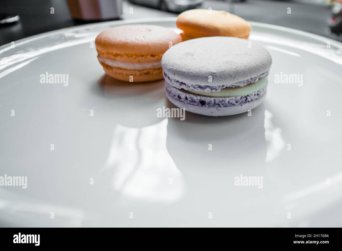 Des macarons de différentes couleurs se trouvent sur une grande assiette blanche plate. Banque D'Images