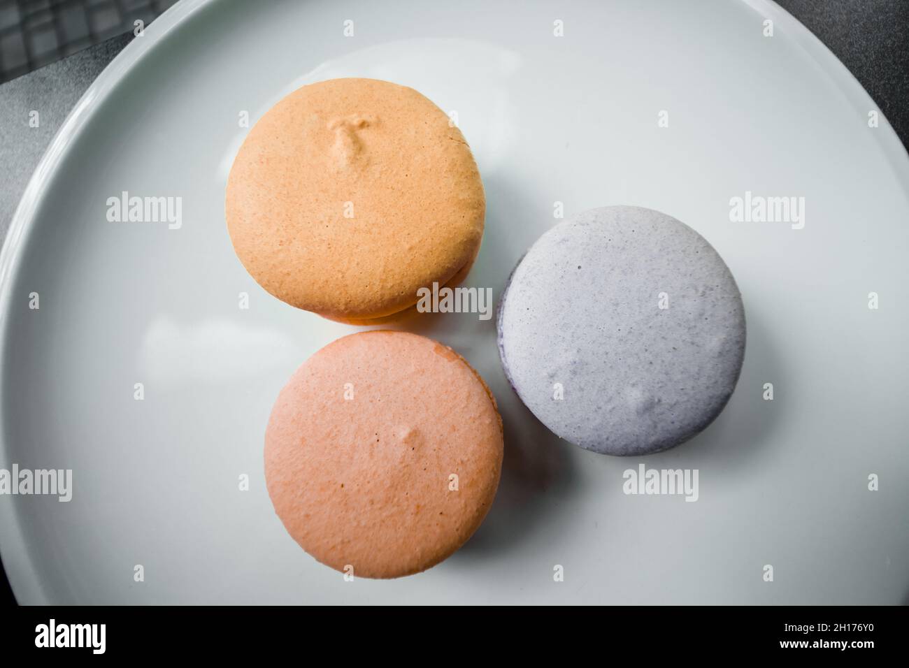 Trois biscuits macareux sont posés sur une assiette blanche dans une pâtisserie. Banque D'Images