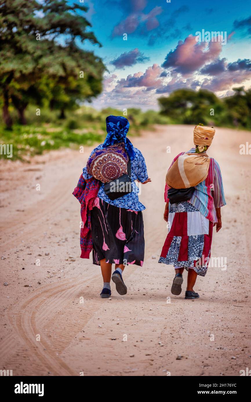 Deux vieux bushman du Kalahari central, village de New Xade au Botswana, marchant sur une route de terre Banque D'Images