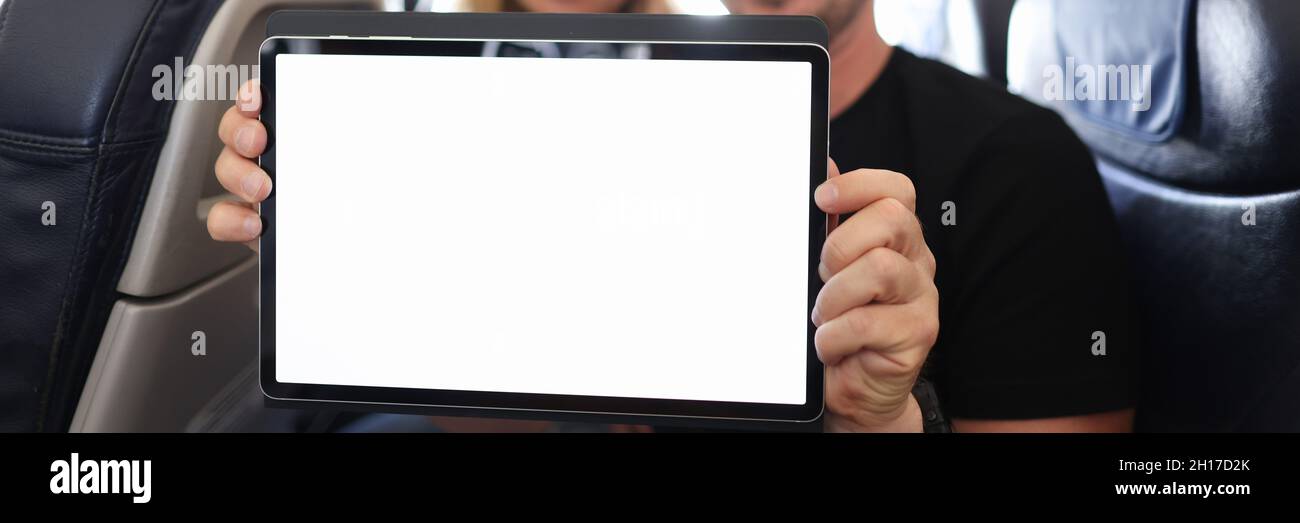 Un jeune homme et une jeune femme en chapeaux du père noël tenant une tablette numérique en cabine d'avion Banque D'Images