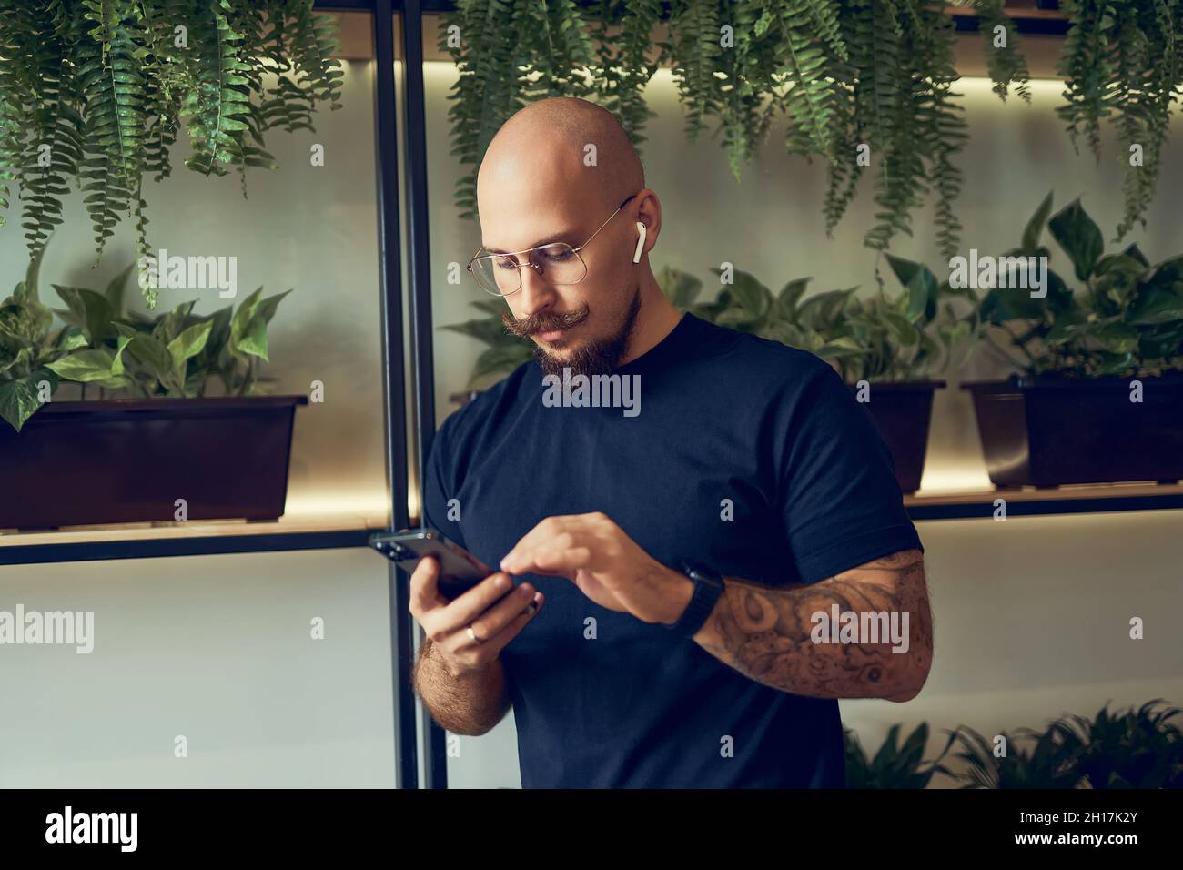Un homme d'affaires concentré utilise un smartphone avec un casque lorsqu'il est au bureau à domicile.Travail à distance. Banque D'Images