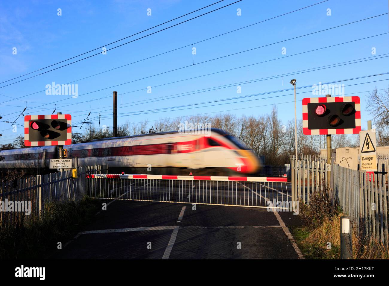 Train Azuma passant les feux rouges à un passage à niveau sans pilote, East Coast main Line Railway, Peterborough, Cambridgeshire, Angleterre, Royaume-Uni Banque D'Images