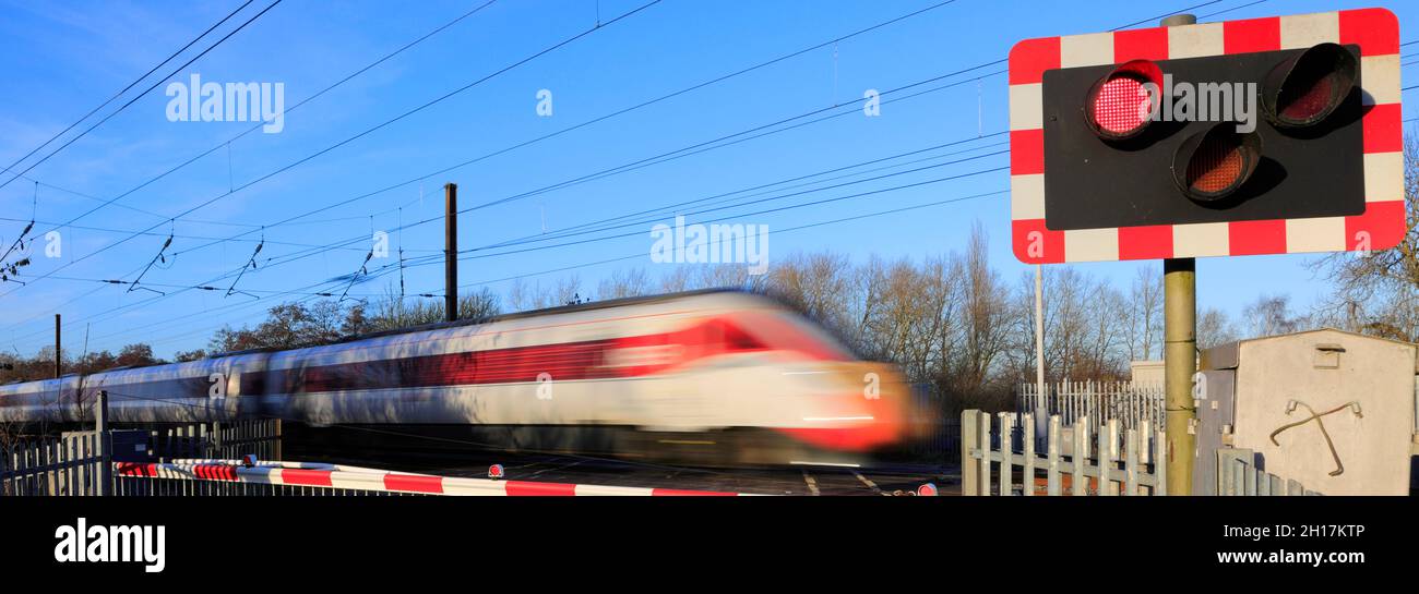 Train Azuma passant les feux rouges à un passage à niveau sans pilote, East Coast main Line Railway, Peterborough, Cambridgeshire, Angleterre, Royaume-Uni Banque D'Images