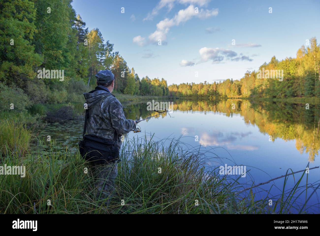 RÉGION DE KOSTROMA, RUSSIE - 19 SEPTEMBRE 2018 : un pêcheur avec une tige de rotation sur la rive d'un lac forestier, dans une soirée ensoleillée de septembre Banque D'Images