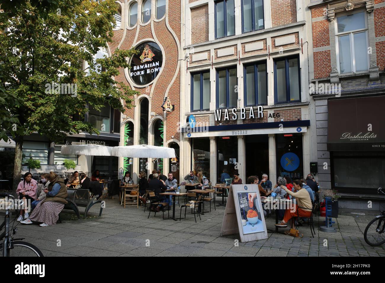 Gand, Belgique - octobre 9.2021: Vue sur la place sur le café restaurant avec les gens assis à l'extérieur le jour ensoleillé (foyer sur le centre du bâtiment) Banque D'Images