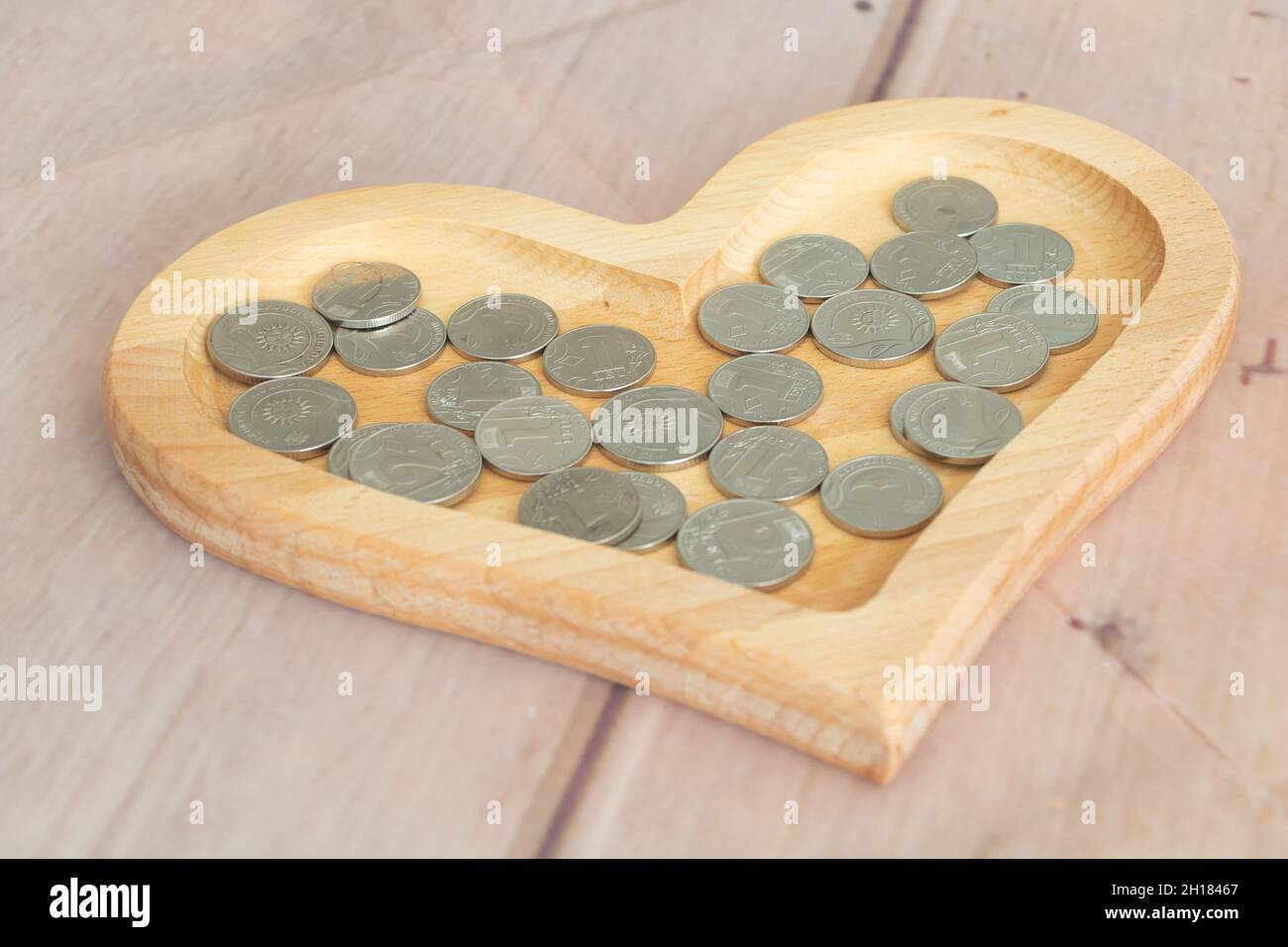 Pièces de monnaie en monnaie lei moldave 1 leu - 2lei dans une assiette en bois en forme de coeur. Banque D'Images