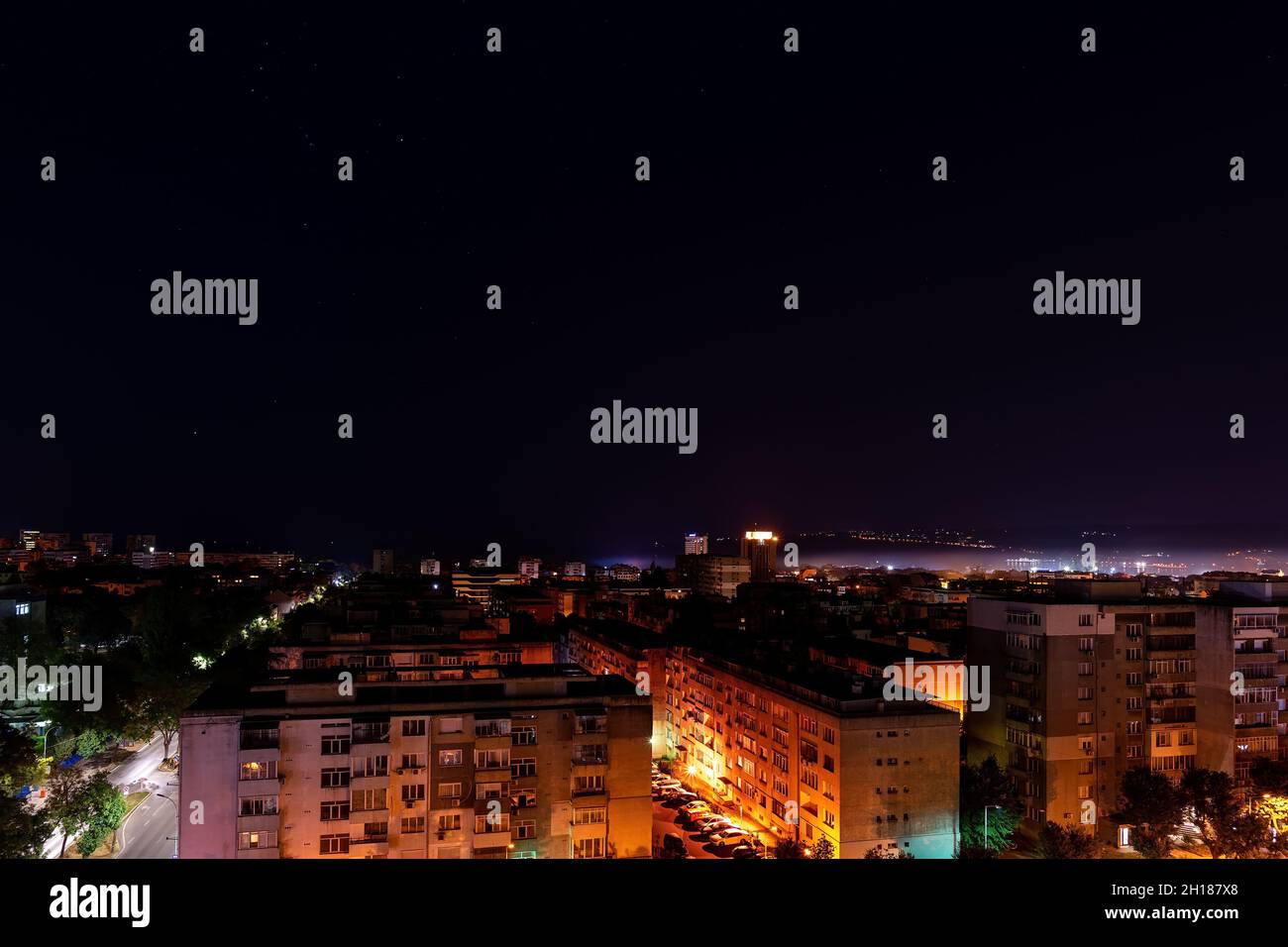 Vue nocturne sur la ville avec vue sur la ville et les bâtiments résidentiels.La constellation Orion brille dans le ciel sombre sur les rues illuminées de Varna. Banque D'Images