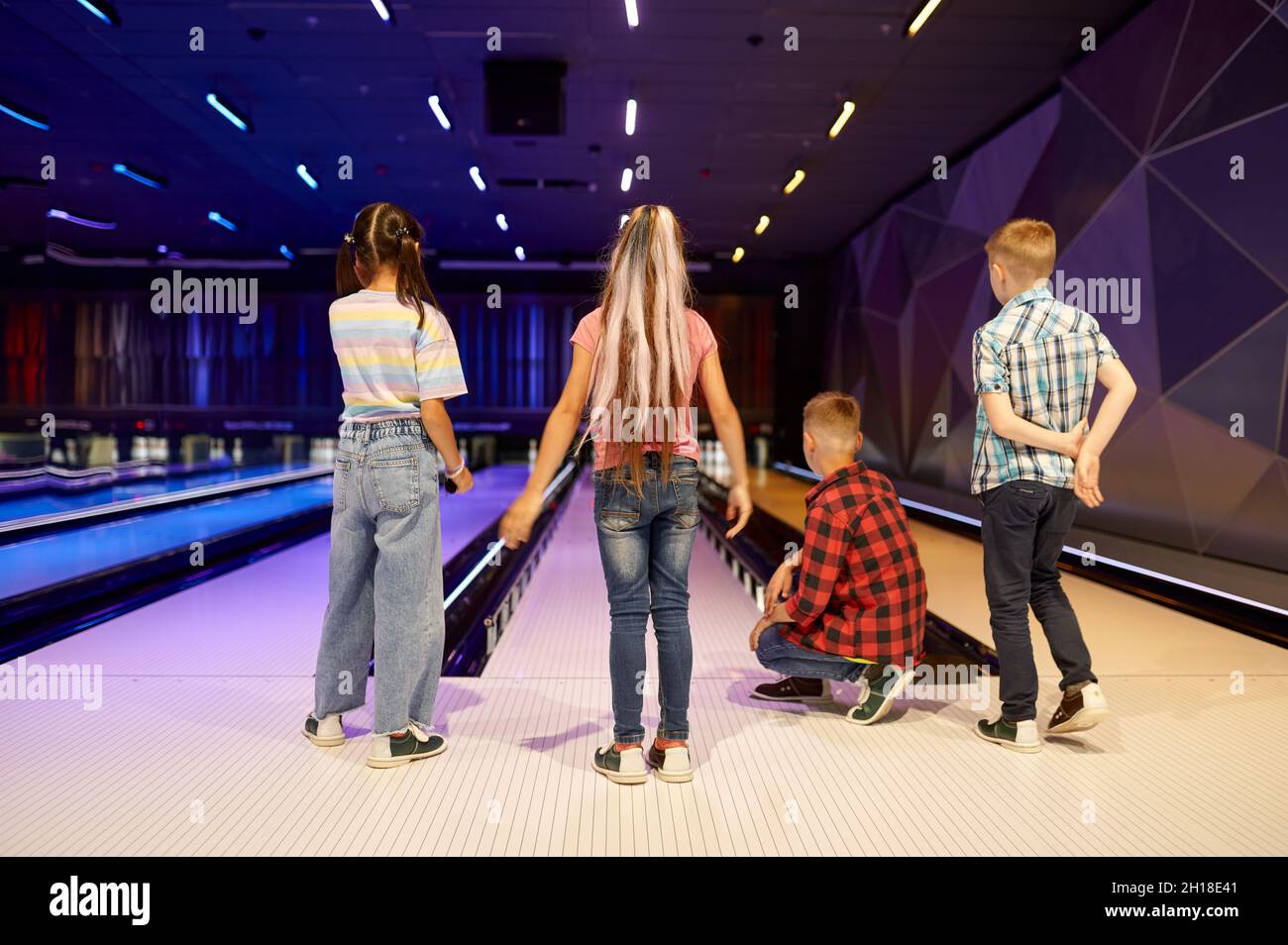 Les enfants lancent une balle sur la voie dans une piste de bowling Banque D'Images