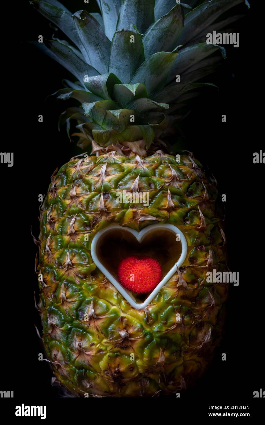 Ananas avec une ouverture en forme de coeur dans son centre avec une madrone mûre à l'intérieur. Banque D'Images