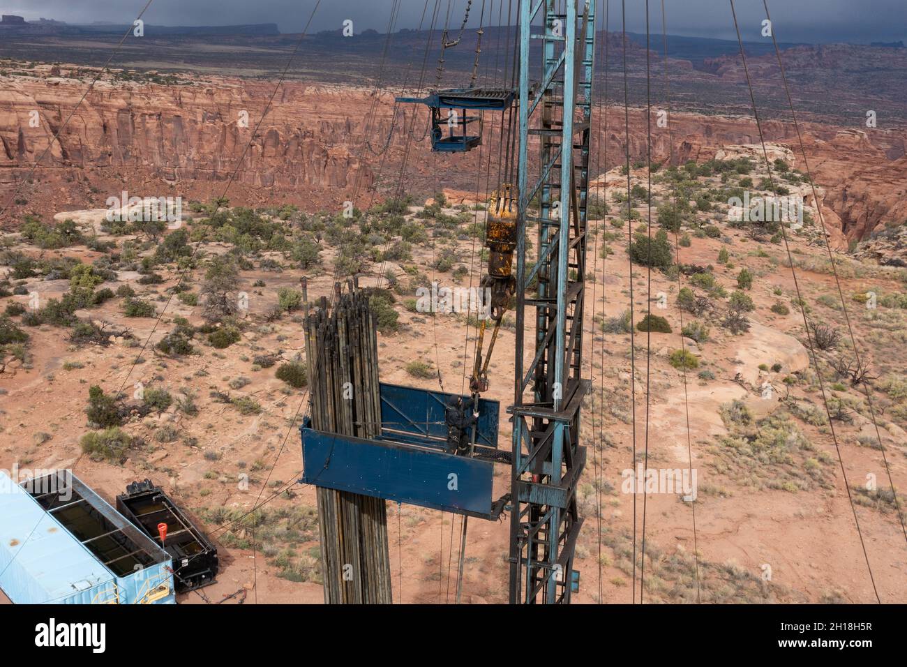 Un derrickman fixe des tubes au bloc de déplacement sur un engin de chantier qui effectue l'entretien d'un puits de pétrole. Banque D'Images