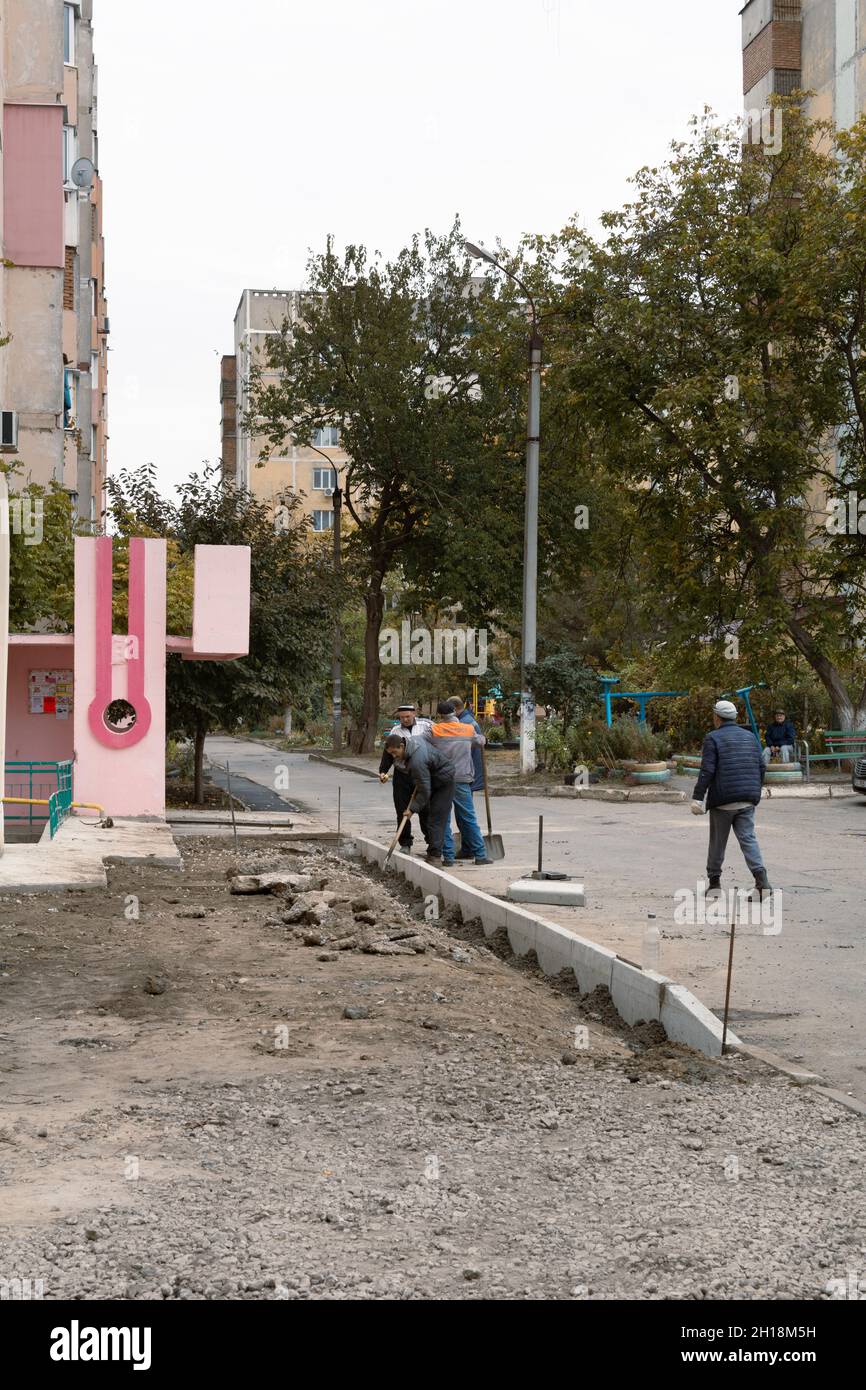 Tiraspol, Moldova - 15 octobre 2021 : les travailleurs des services routiers installent de nouvelles bordures en béton dans la cour d'un immeuble d'appartements dans la capitale du Banque D'Images