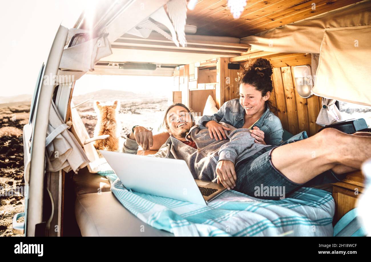 Couple nomade numérique voyageant avec un chien sur un transport de minibus rétro - concept de style de vie Freedom avec des personnes indé sur une aventure en minibus Banque D'Images