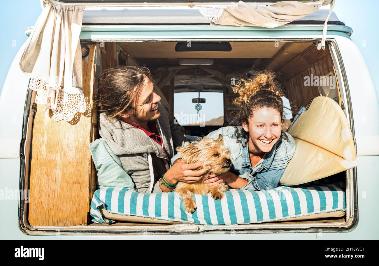 Un petit couple avec un adorable chien voyageant ensemble sur un minibus d'époque - concept d'inspiration de la vie avec les hippie lors d'un voyage aventure en minibus Banque D'Images