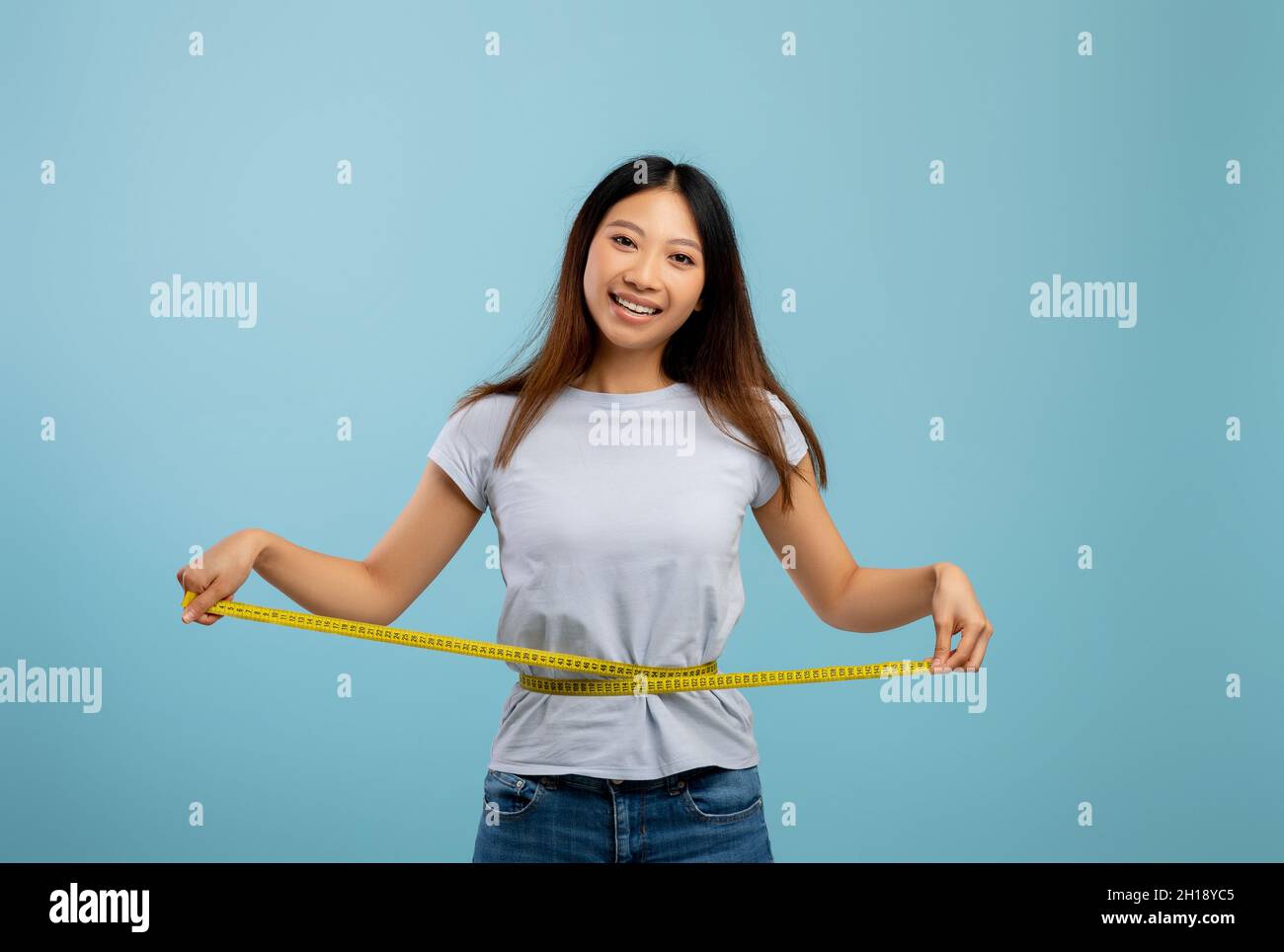 Concept de perte de poids.S'adapte asiatique femme mesurant sa taille avec du ruban adhésif sur fond bleu studio Banque D'Images