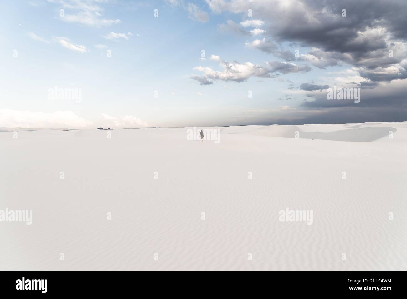 Un homme qui marche à travers les dunes de sable au parc national de White Sands à Alamogordo, Nouveau-Mexique. Banque D'Images