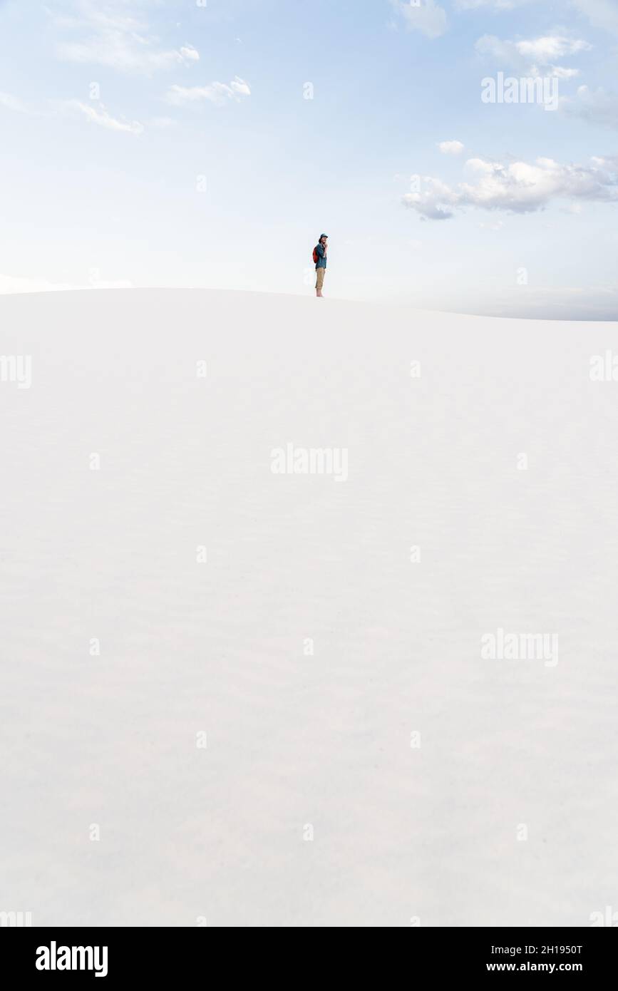 Un homme qui marche à travers les dunes de sable au parc national de White Sands à Alamogordo, Nouveau-Mexique. Banque D'Images