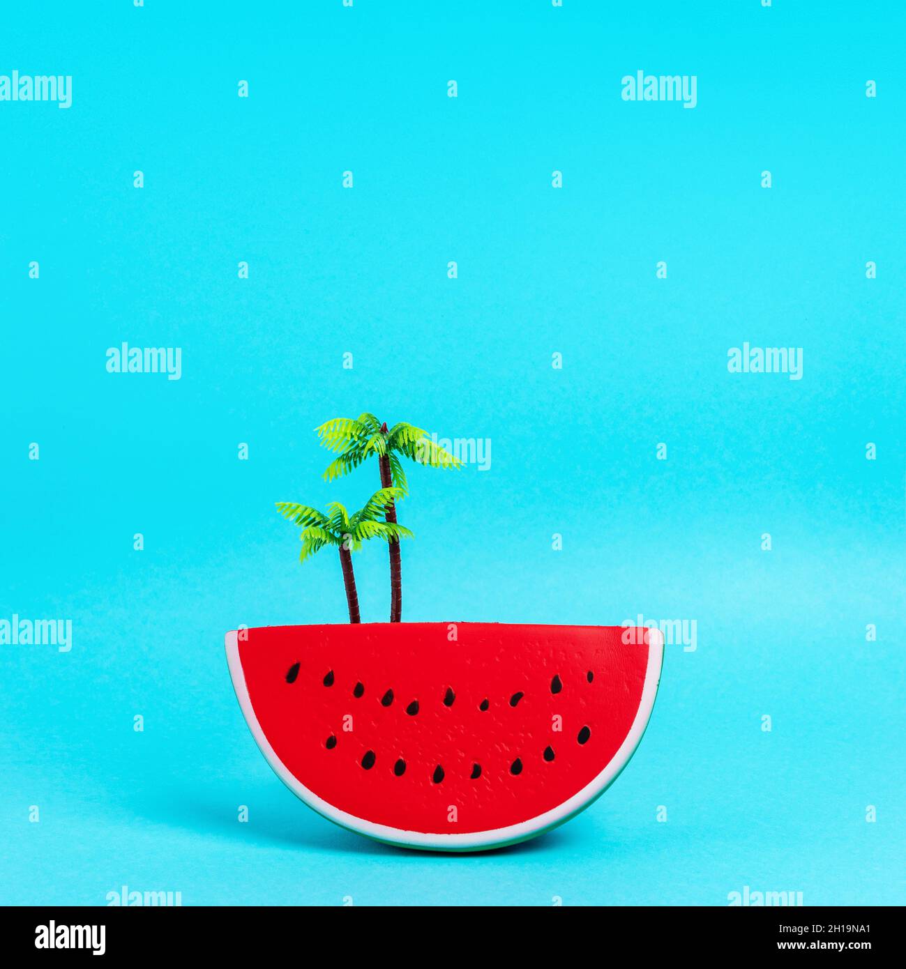 Fruit de pastèque avec jouet en plastique de palmier sur fond bleu pastel.Concept d'été minimaliste créatif. Banque D'Images