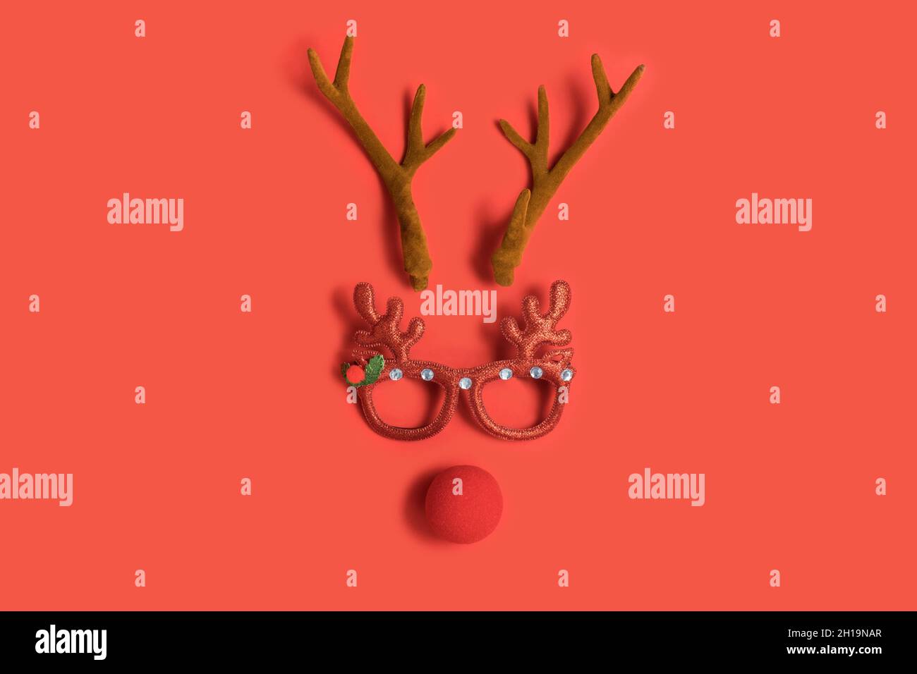 Drôle de visage de Noël avec des bois d'un cerf, des lunettes de jouet et  un nez clown sur un fond rouge Photo Stock - Alamy