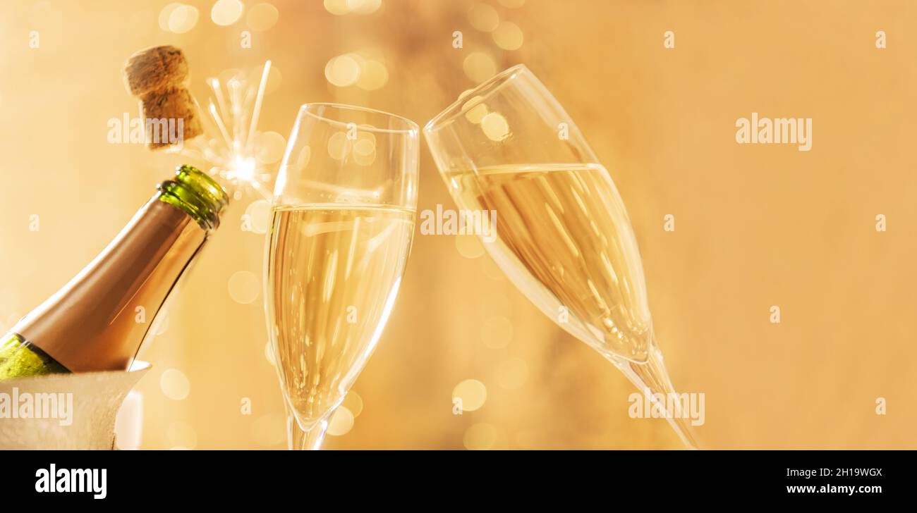 Deux verres de champagne toasting tandis que le liège sort de la bouteille de champagne Banque D'Images