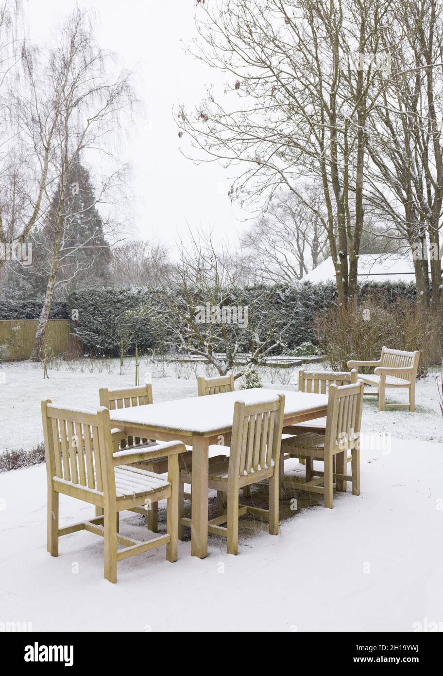 Chute de neige sur le mobilier de jardin en hiver, Royaume-Uni.Table et chaises en bois de teck dans une grande cour arrière Banque D'Images