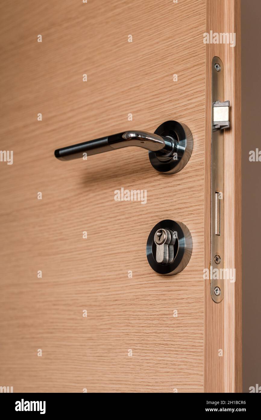 Poignée de porte métallique moderne sur porte de chambre en carton de densité moyenne, mise au point sélective Banque D'Images