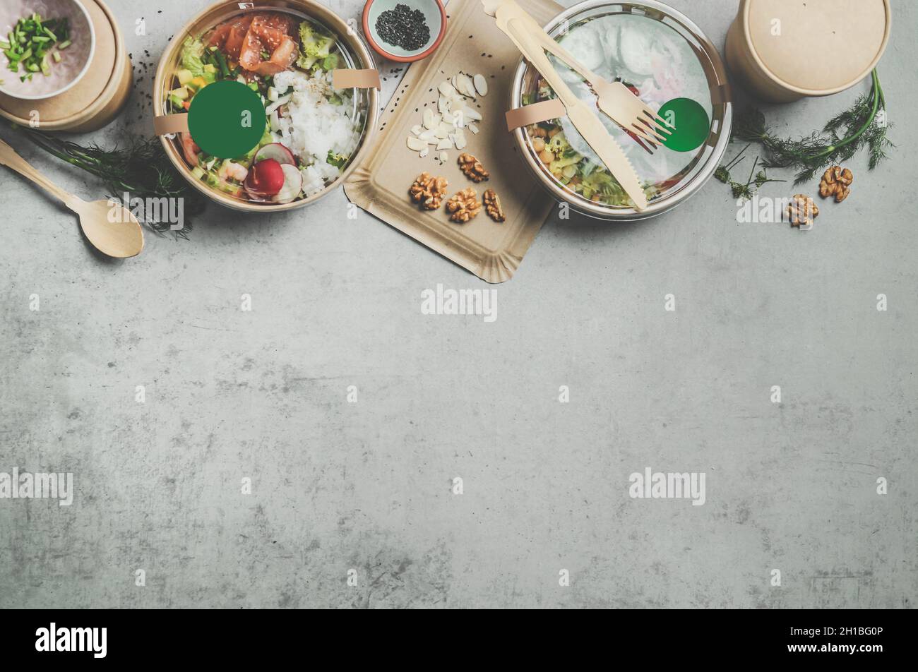 Divers conteneur d'aliments durables avec des aliments sains sur table de cuisine en béton gris.Service de livraison moderne avec couverts en bois et boîte en papier Banque D'Images