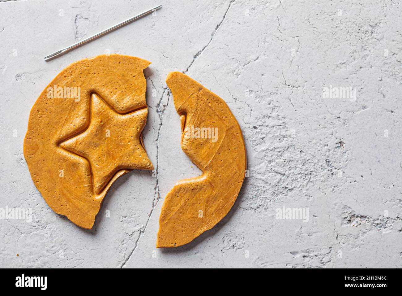 Dalgona Candy - régal sud-coréen.Cookie de sucre rond avec une étoile à l'intérieur, vue du dessus. Banque D'Images