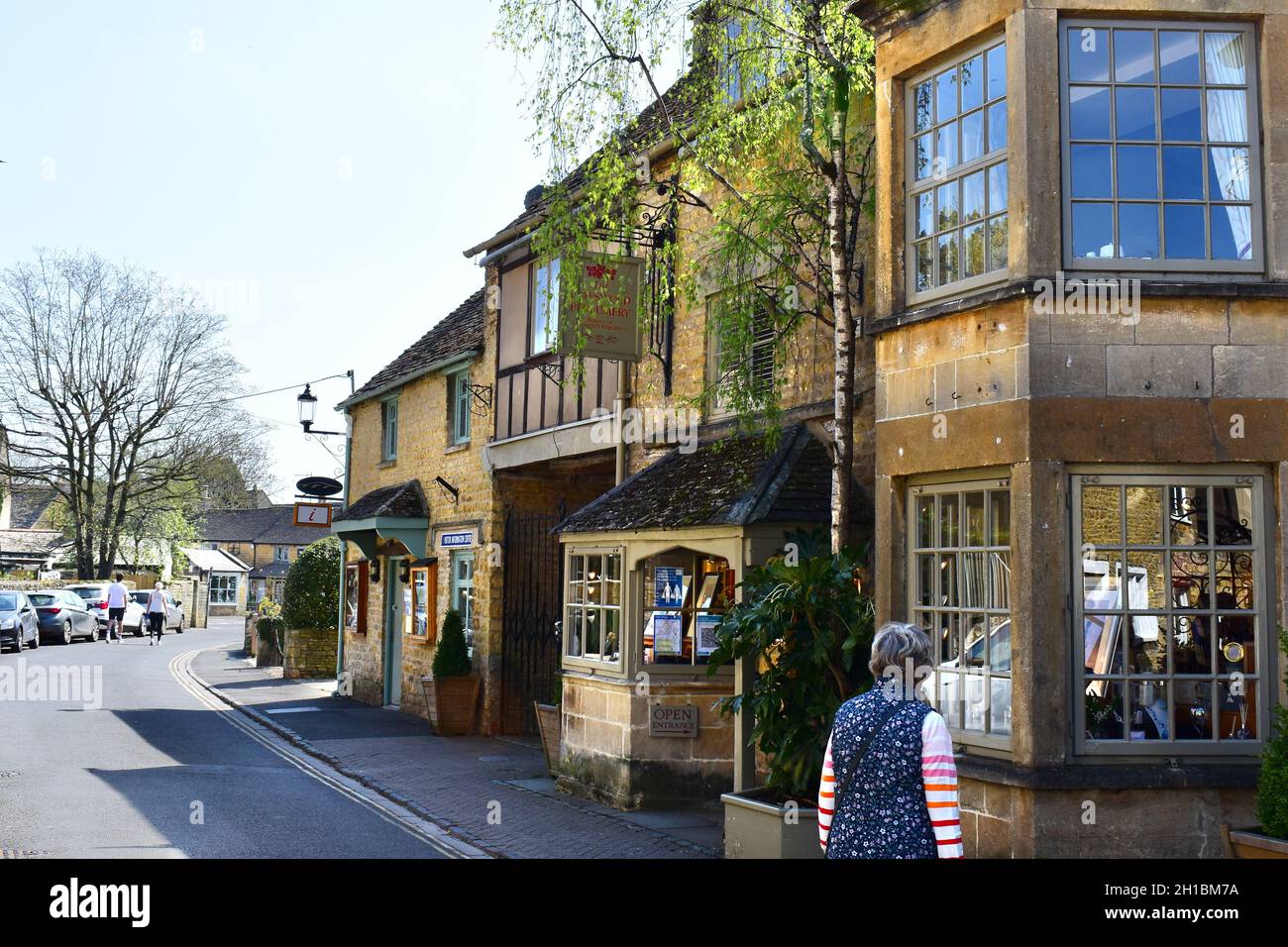 Vue sur les boutiques et les cafés le long de l'une des rues du centre de ce magnifique village de Cotswold. Banque D'Images