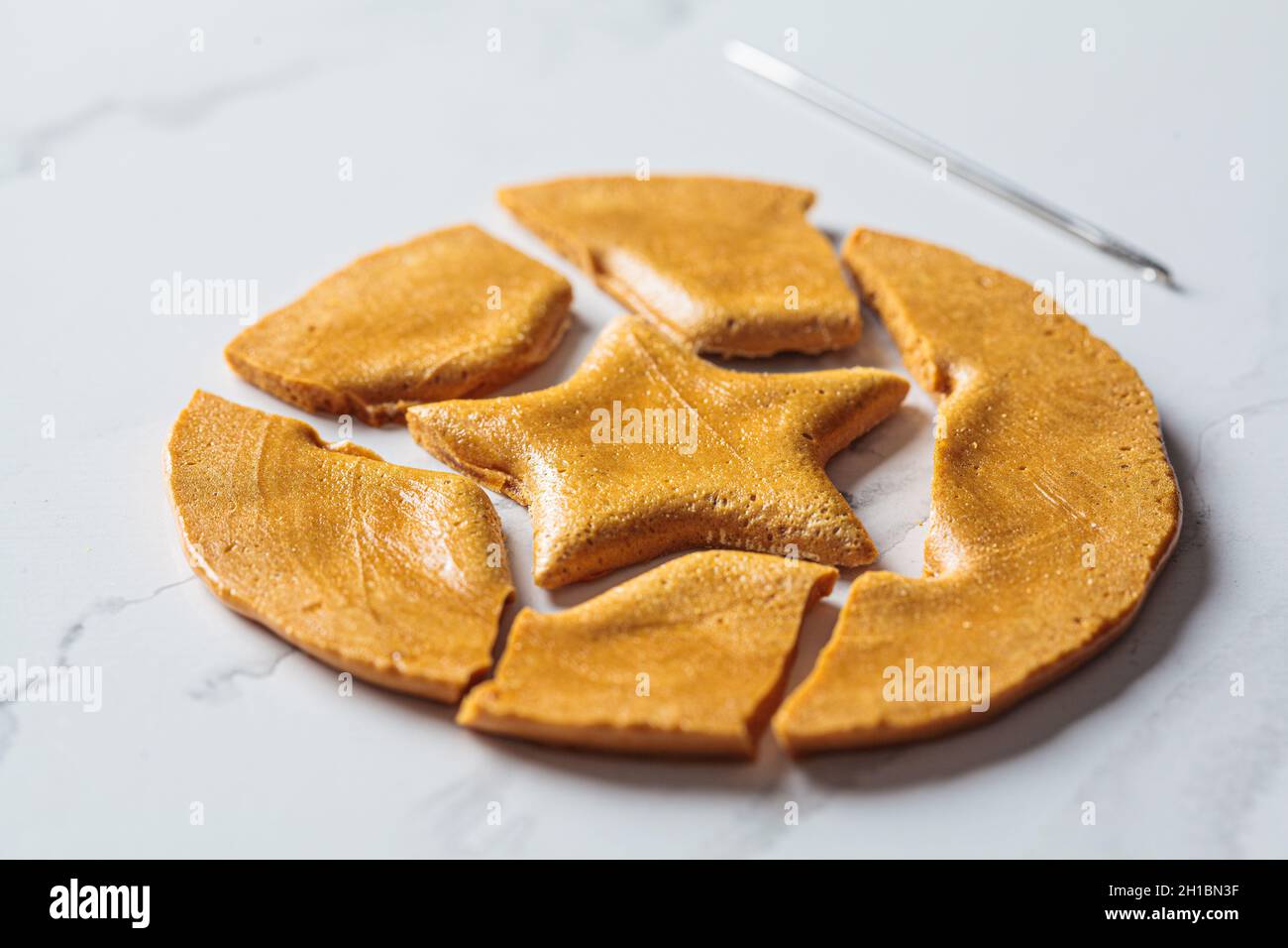 Dalgona Candy - régal sud-coréen.Biscuit au sucre rond avec une étoile à l'intérieur, gros plan. Banque D'Images