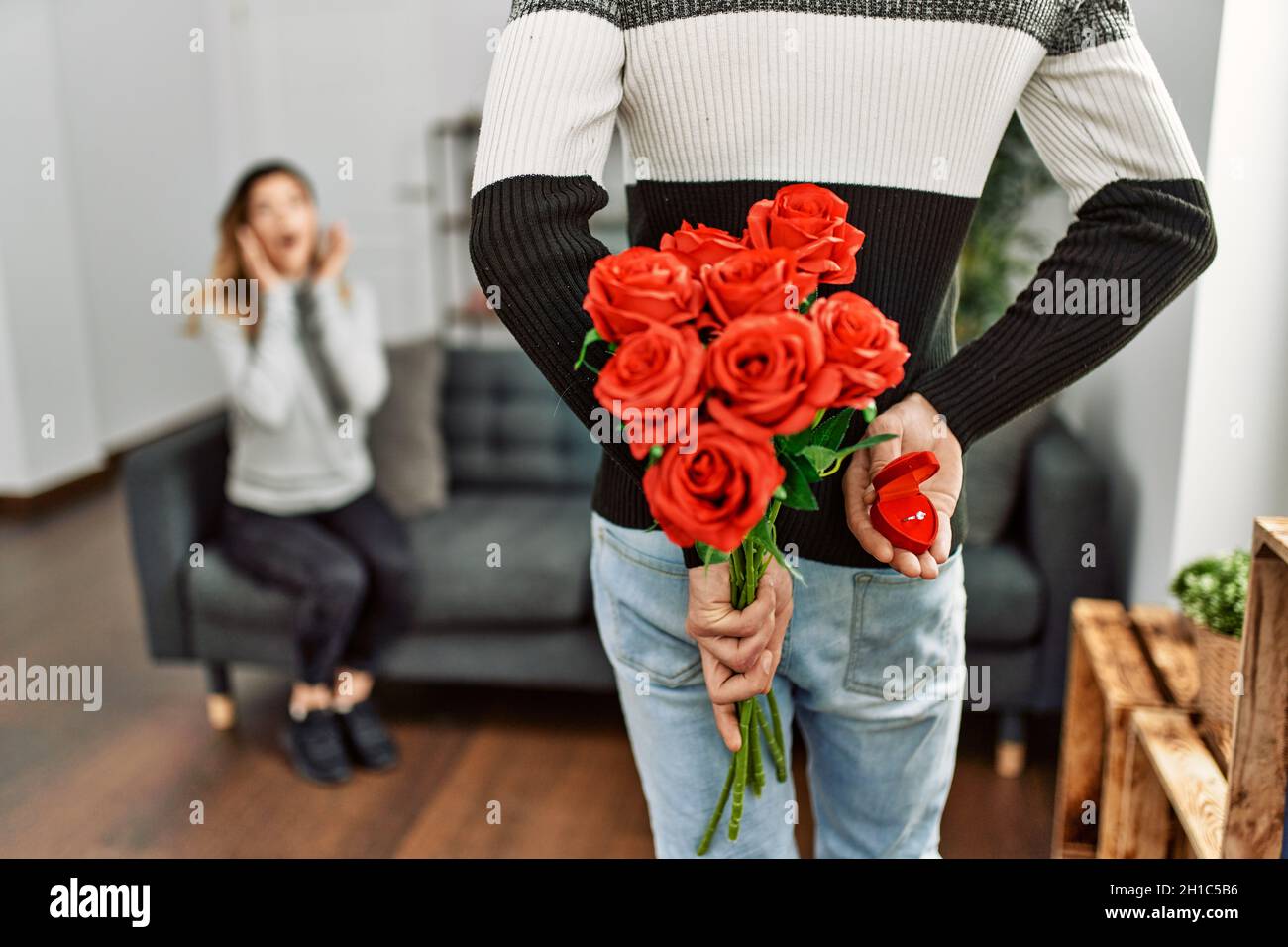 Homme femme suprising avec bouquet de roses et anneau d'engagement à la maison. Banque D'Images