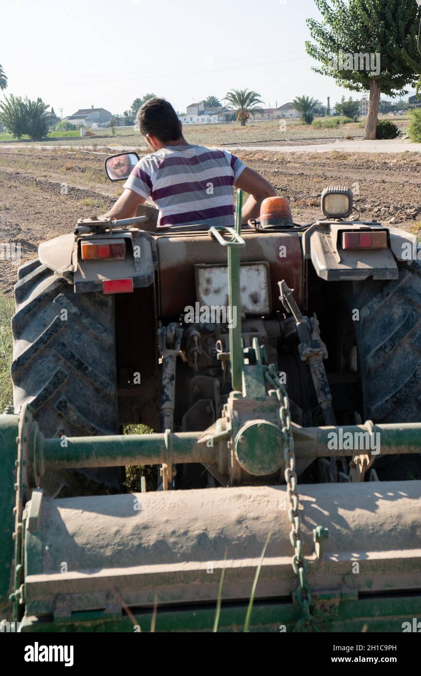 jeune agriculteur cultivant le champ sur son tracteur . Banque D'Images