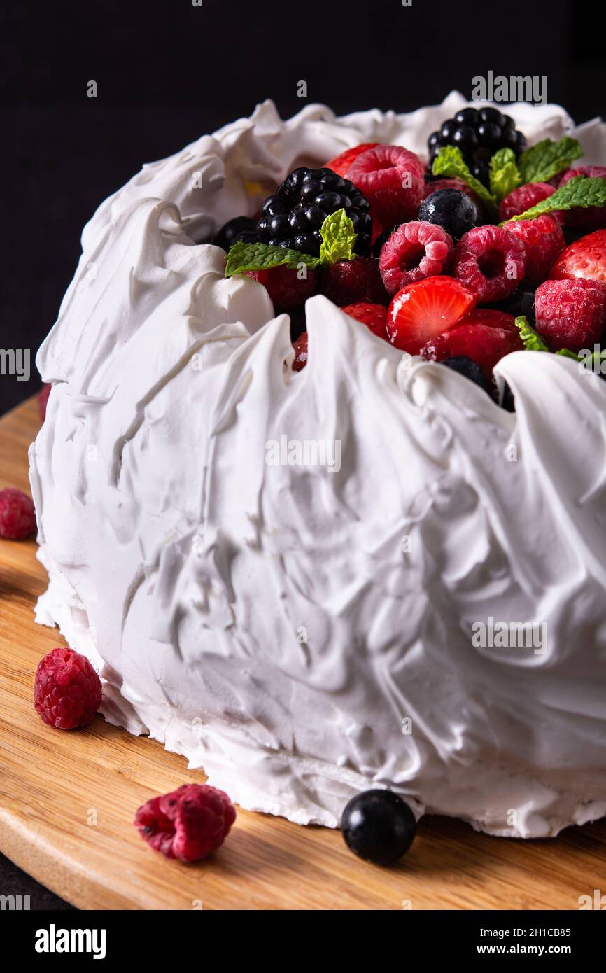 Délicieux gâteau Pavlova avec surfinition meringue et baies fraîches sur fond noir Banque D'Images