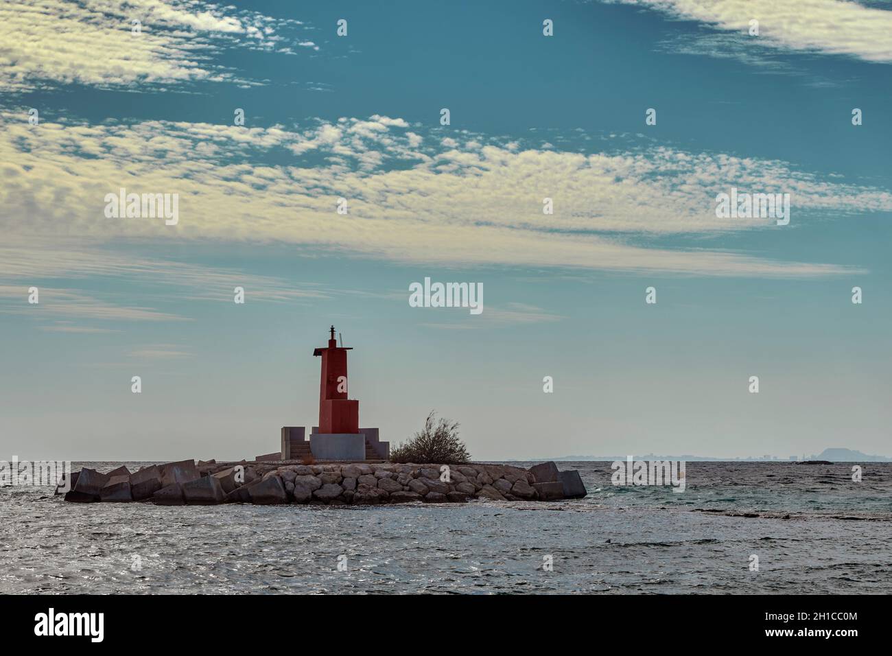 Phare rouge à l'entrée du port de Villajoyosa par une journée nuageux et ensoleillée dans la province d'Alicante, Espagne, Europe Banque D'Images