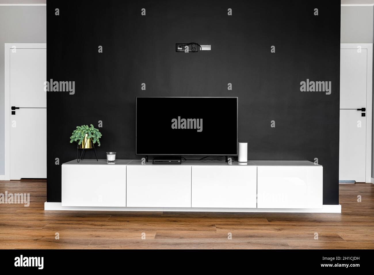 Mur noir mat de télévision dans le salon avec un téléviseur sur pied sur un meuble blanc suspendu. Banque D'Images