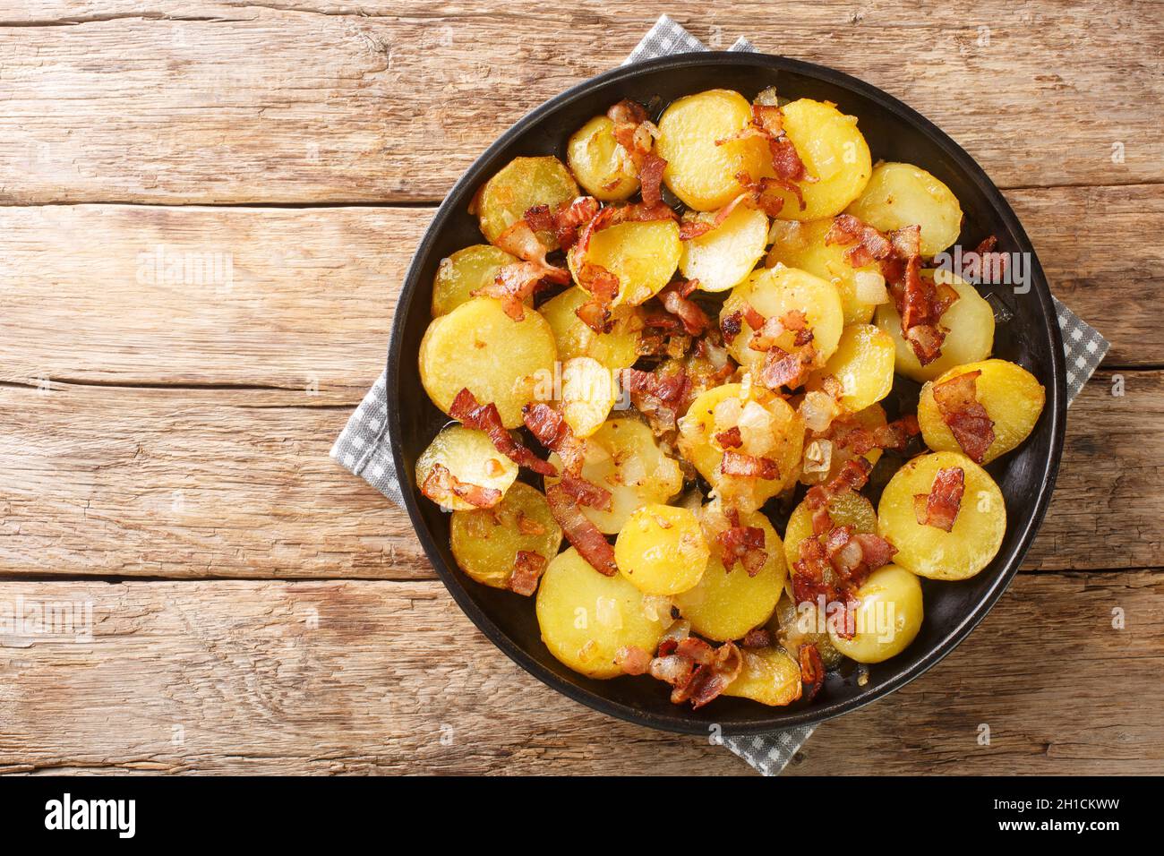 Pommes de terre frites ou Bratkartoffeln au bacon et à l'oignon, dans l'assiette de la table.Vue horizontale du dessus Banque D'Images