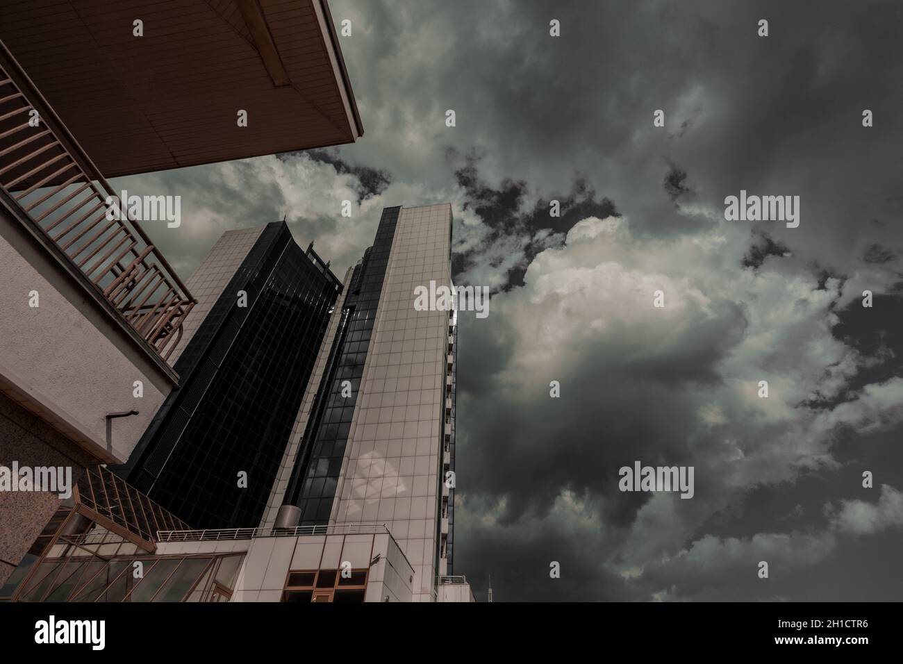 Un haut bâtiment de plusieurs étages sur fond de ciel gris sombre et nuageux. Banque D'Images