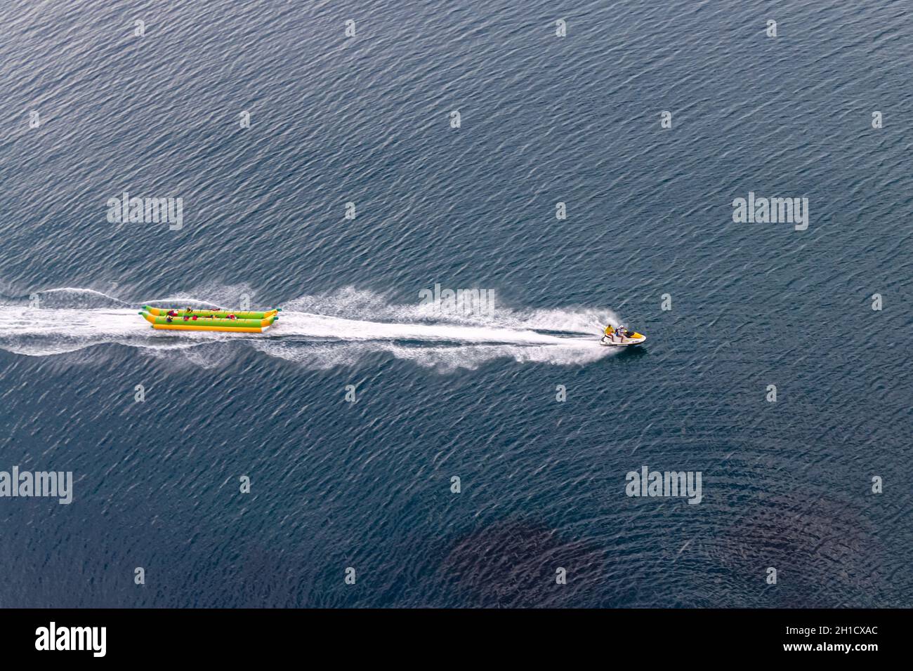Le jet ski tracte un banana boat gonflable à travers la mer, laissant un sentier blanc derrière.Vue de dessus.Une des activités de la mer r Banque D'Images